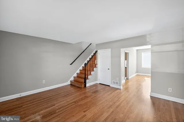 a view of an empty room with wooden floor and stairs