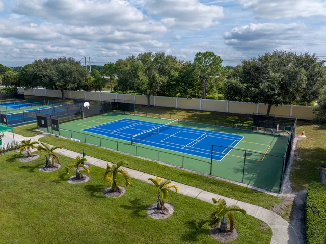 a view of a pool with lawn chairs plants and wooden fence