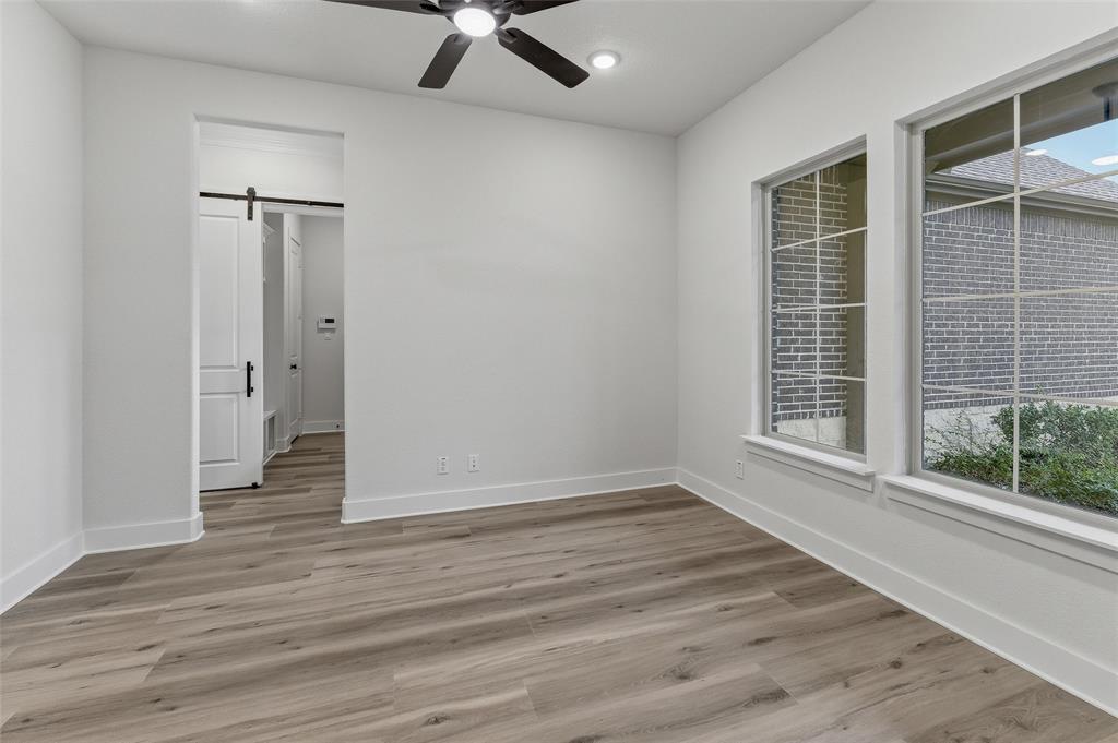 2208 Continent Court Krum, TX 76249 - Photo 6 of 26 Spacious room featuring wood-finish flooring, white walls, and a ceiling fan with integrated lighting