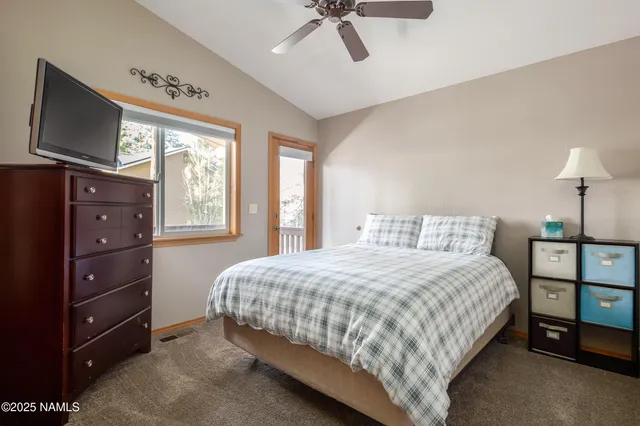 a bedroom with a bed and a flat tv screen on a dresser