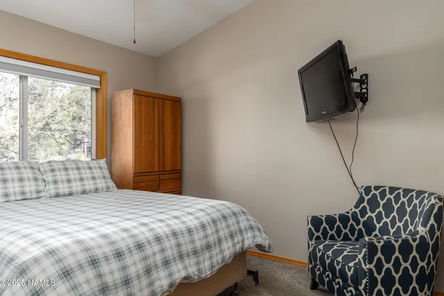 a bedroom with a bed and a flat tv screen on the dresser