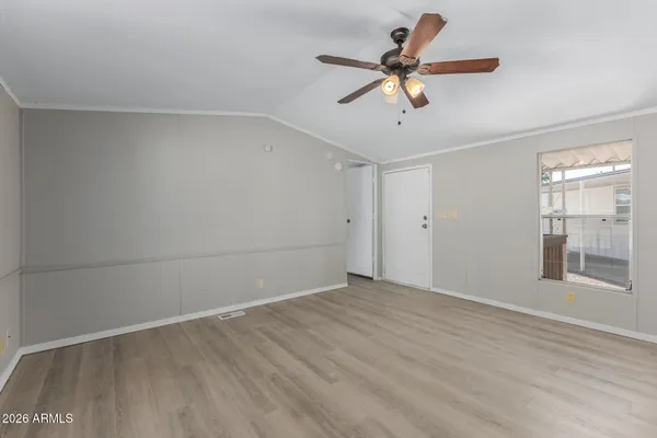 a view of empty room with wooden floor and fan