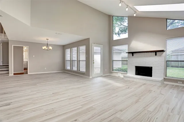 an empty room with wooden floor fireplace and windows