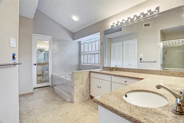 a bathroom with a granite countertop double vanity sink and a mirror