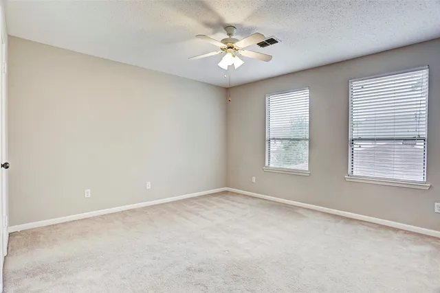an empty room with windows and ceiling fan