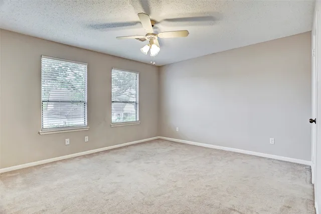 an empty room with windows and chandelier fan