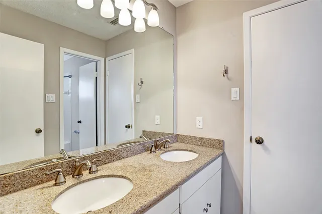 a bathroom with a granite countertop double vanity sink and a mirror