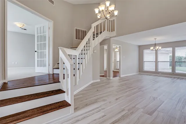 wooden floor in an empty room with a chandelier