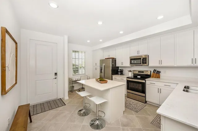 a kitchen with stainless steel appliances kitchen island granite countertop a sink stove and refrigerator