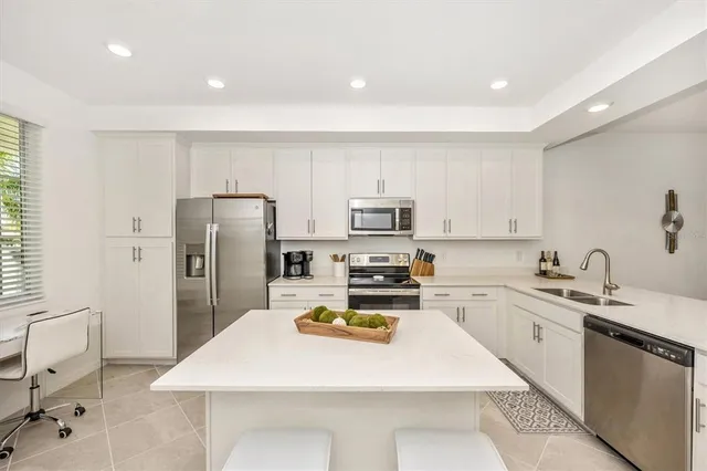 a kitchen with a sink a stove a refrigerator and white cabinets