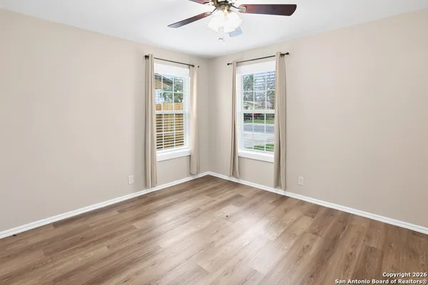 an empty room with wooden floor fan and windows