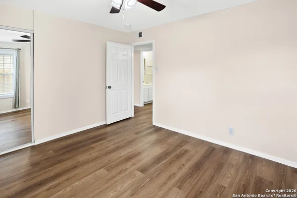 an empty room with wooden floor cabinet and windows
