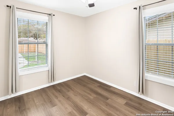 a view of empty room with wooden floor and fan