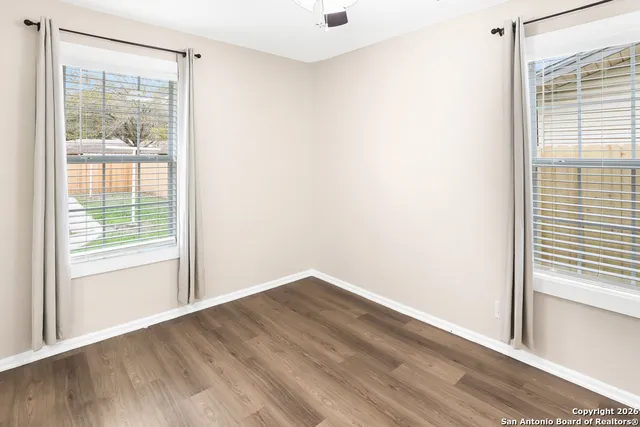 a view of empty room with wooden floor and fan