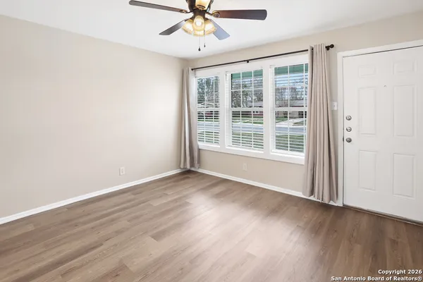 a view of an empty room with wooden floor and a window