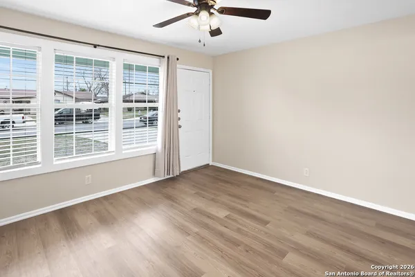 a view of an empty room with a window and wooden floor