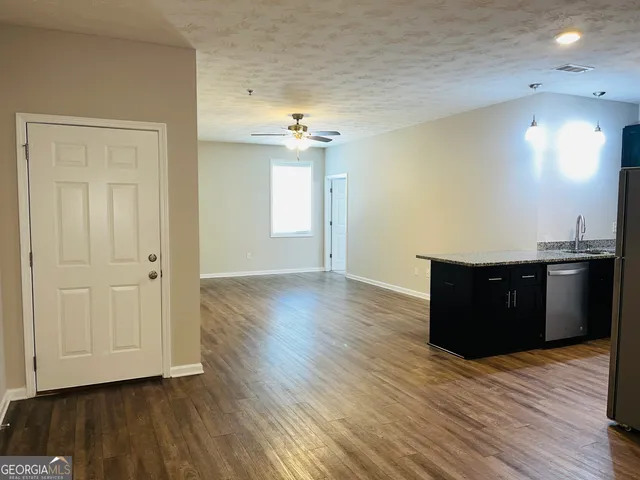 a view of a kitchen with a fridge and wooden floor