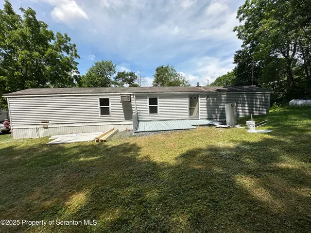 a front view of house with yard and trees in the background