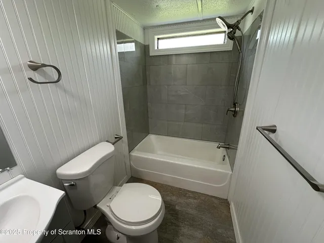a white toilet sitting next to a bath tub