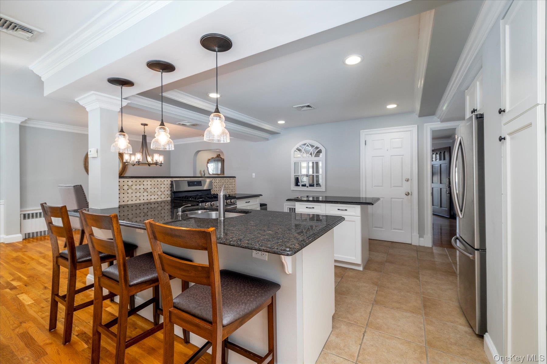 122 Pine Street Rockville Centre, NY 11570 - Photo 11 of 27 a kitchen with stainless steel appliances kitchen island granite countertop a table chairs and a refrigerator