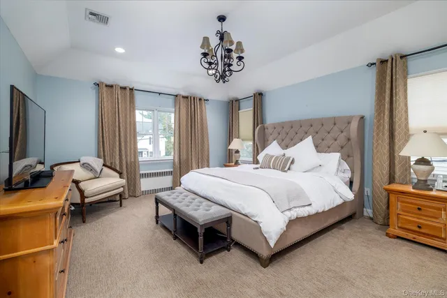 a spacious bedroom with a bed and a chandelier