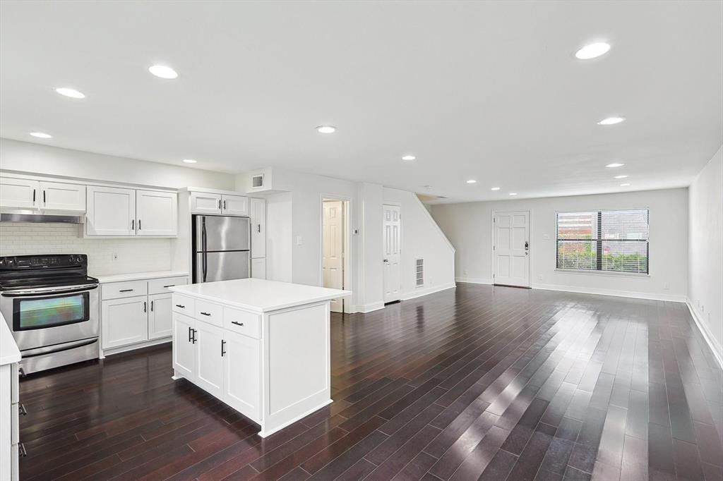 a kitchen with stainless steel appliances a white stove top oven cabinets and a wooden floor