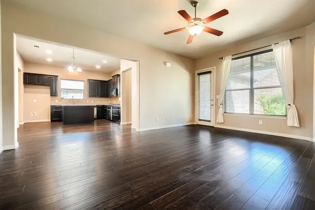 a view of an empty room with kitchen and window