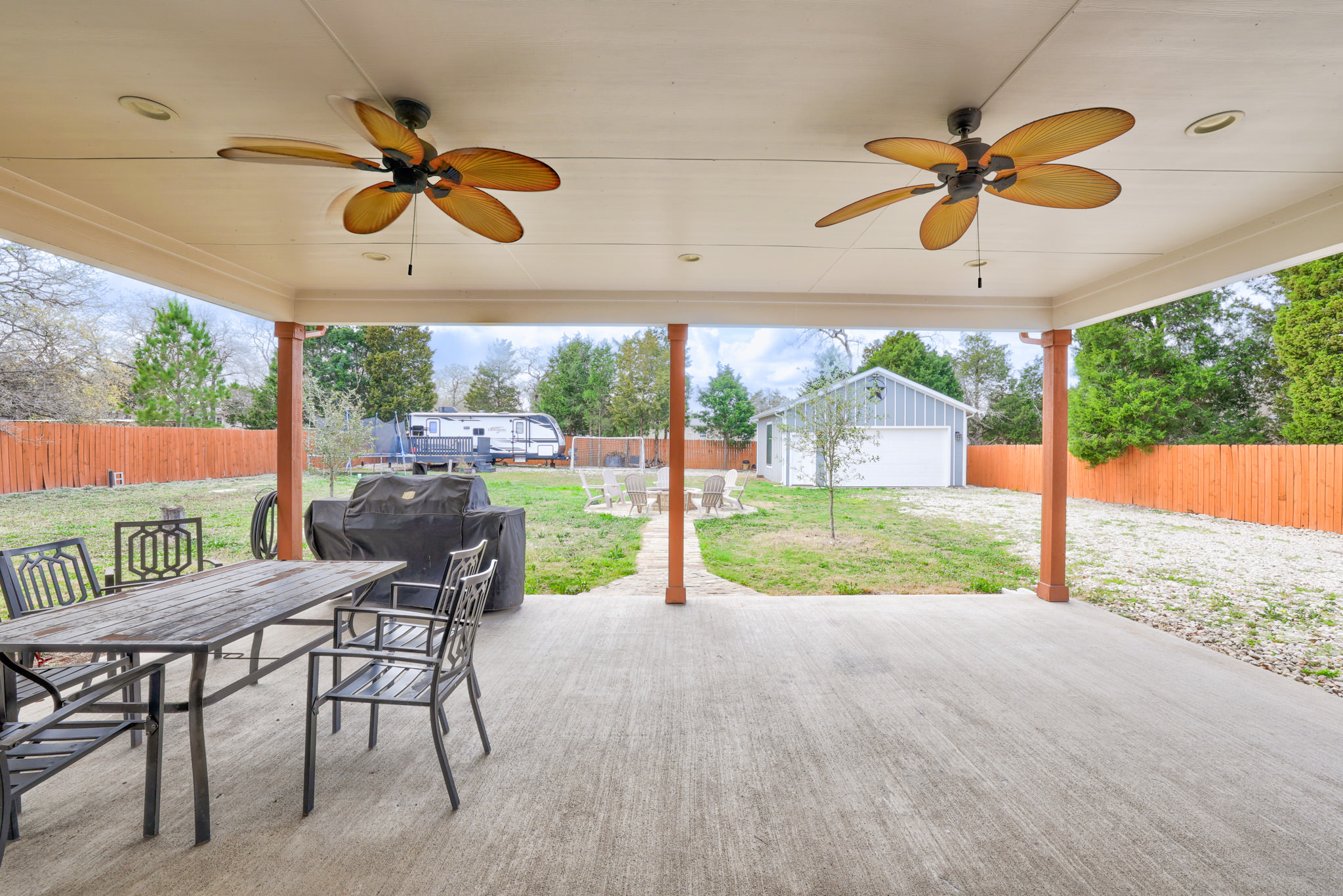 421 Las Lomas Drive Elgin, TX 78621 - Photo 22 of 30 Fenced backyard with outdoor dining space, a ceiling fan, a patio area, an outbuilding, and a garage
