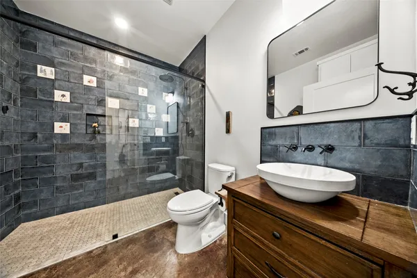 a bathroom with a granite countertop sink a toilet a mirror and shower