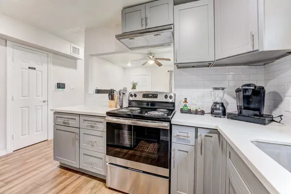 a kitchen with white cabinets stainless steel appliances and wooden floor