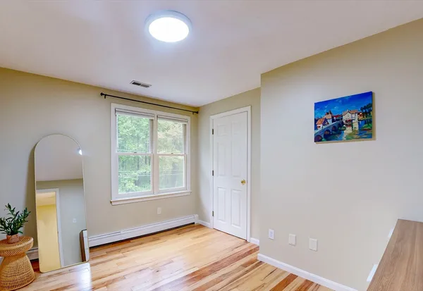 a view of an empty room with a window and wooden floor