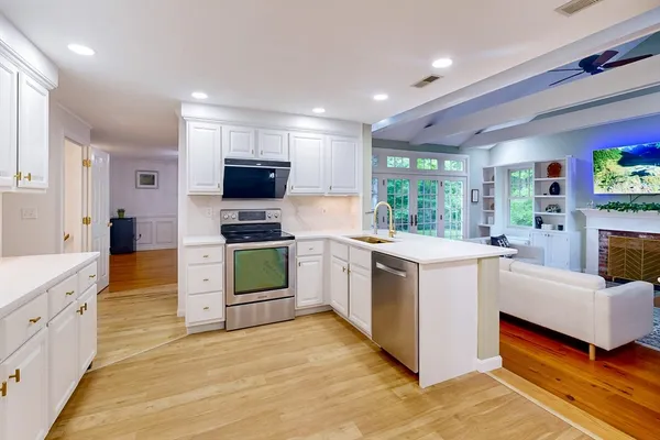 a large kitchen with stainless steel appliances granite countertop a stove a sink and a microwave