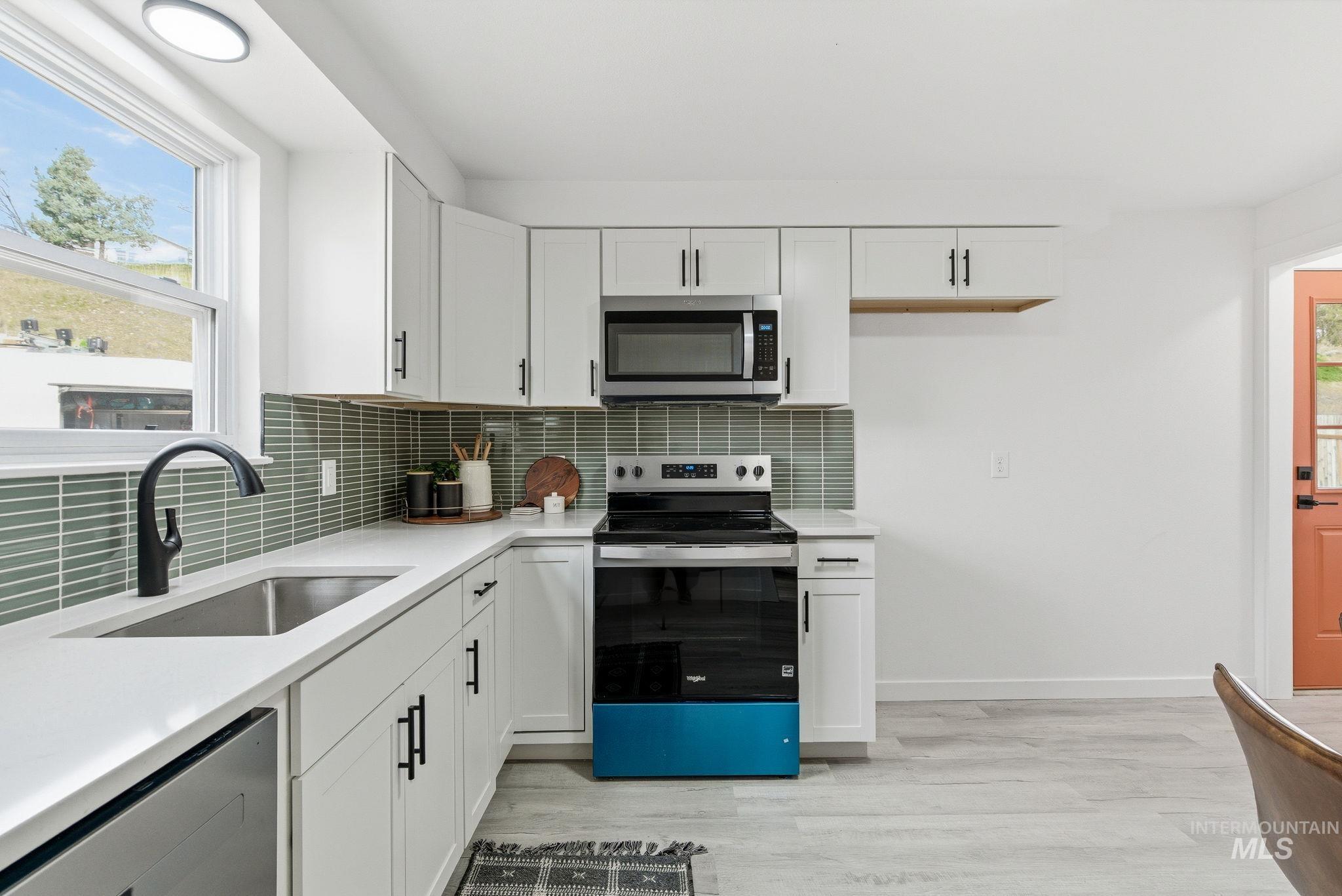 6123 South Brian Way Boise, ID 83716 - Photo 17 of 50 Kitchen featuring stainless steel appliances, white cabinets, light stone countertops, and light wood-type flooring
