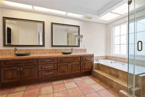 a spacious bathroom with a granite countertop double vanity sink a mirror and a bathtub