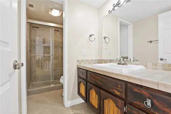 a bathroom with a granite countertop sink a mirror and a shower