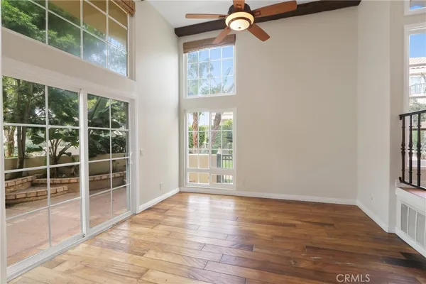 a view of an empty room with a window and wooden floor
