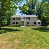 a view of a house with a big yard and large trees