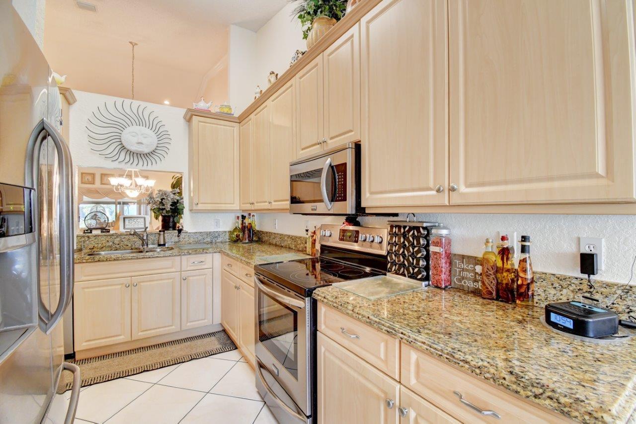 6104 Caladium Road Delray Beach, FL 33484 - Photo 12 of 43 a kitchen with stainless steel appliances granite countertop a sink and cabinets