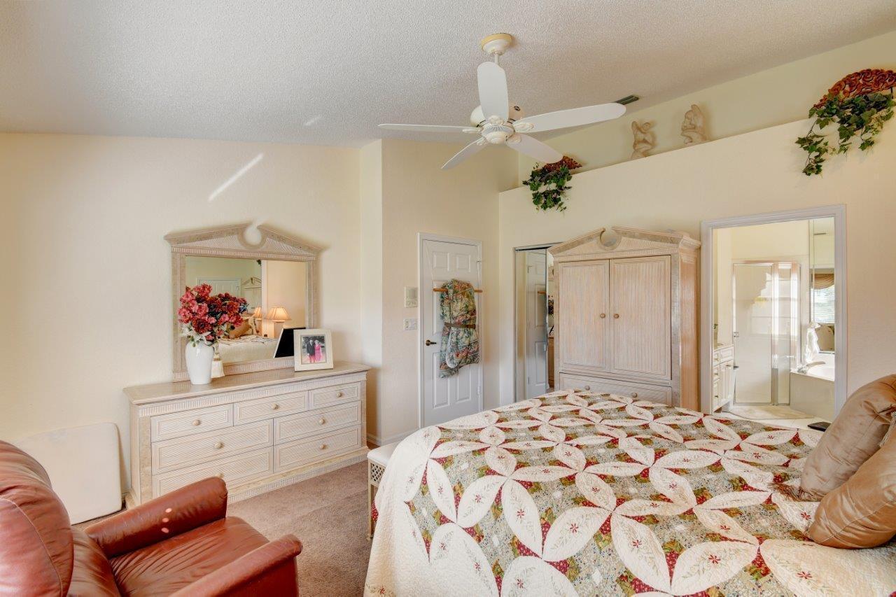 6104 Caladium Road Delray Beach, FL 33484 - Photo 16 of 43 a bedroom with a bed and a chandelier
