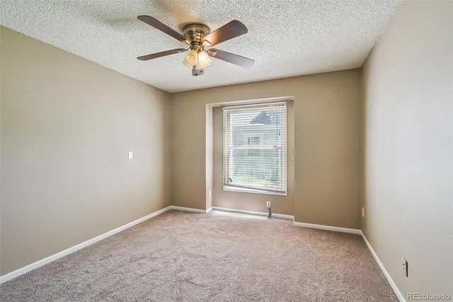 an empty room with a chandelier fan and windows