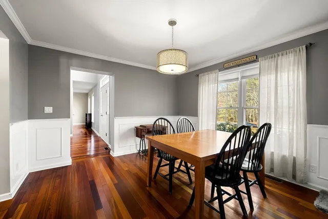 a dining room with wooden floor a chandelier a wooden table and chairs