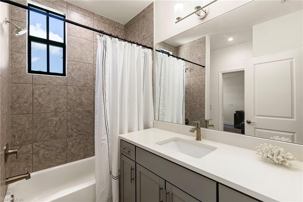 7622 Rockefeller Drive Naples, FL 34119 - Photo 25 of 35 a bathroom with a granite countertop sink and a bathtub