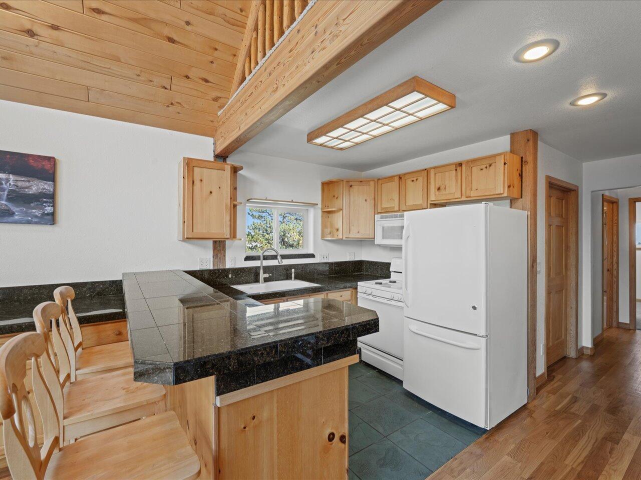 55 Valley View Road Ridgway, CO 81432 - Photo 13 of 39 a kitchen with stainless steel appliances granite countertop a stove a refrigerator a sink dishwasher and white countertops with wooden floor