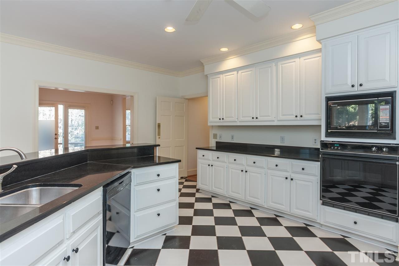 2008 Tradd Court Raleigh, NC 27607 - Photo 10 of 25 a kitchen with granite countertop white cabinets and black appliances