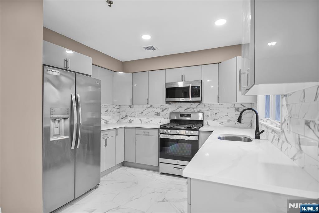 75 West Columbia Avenue, Unit 2 Palisades Park, NJ 07650 - Photo 5 of 27 a kitchen with stainless steel appliances granite countertop a refrigerator sink and stove