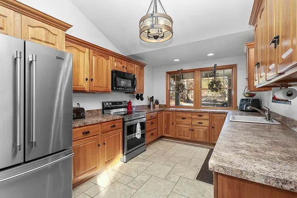 a large kitchen with stainless steel appliances granite countertop a stove top oven a refrigerator a sink and dishwasher with wooden floor