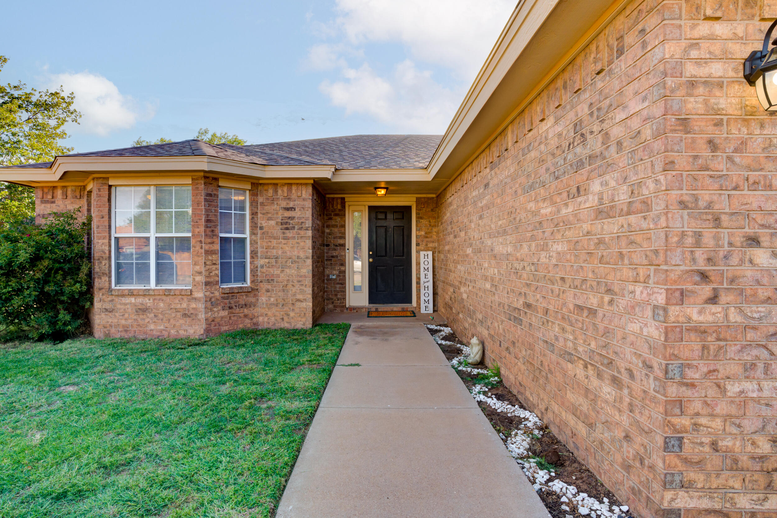8406 Canton Avenue Lubbock, TX 79423 - Photo 24 of 25 a view of a house with brick walls and a yard with table and chairs