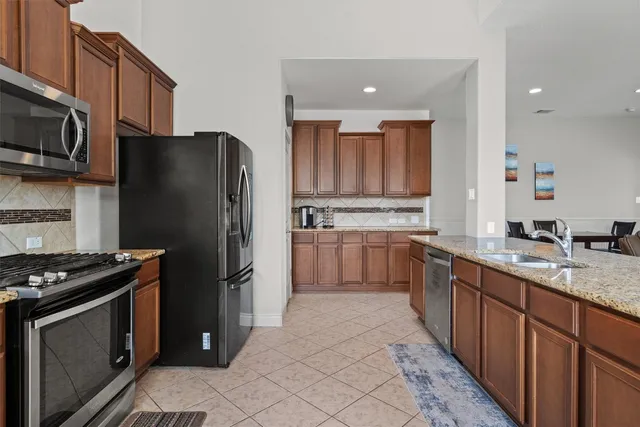 a kitchen with stainless steel appliances granite countertop a refrigerator stove top oven a sink and dishwasher