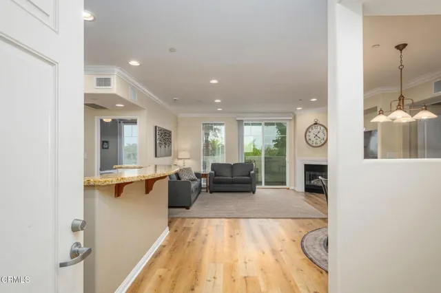 a kitchen with stainless steel appliances granite countertop a stove a refrigerator a kitchen island a dining table and chairs with wooden floor