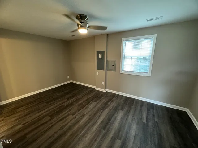 a view of an empty room with wooden floor and a window
